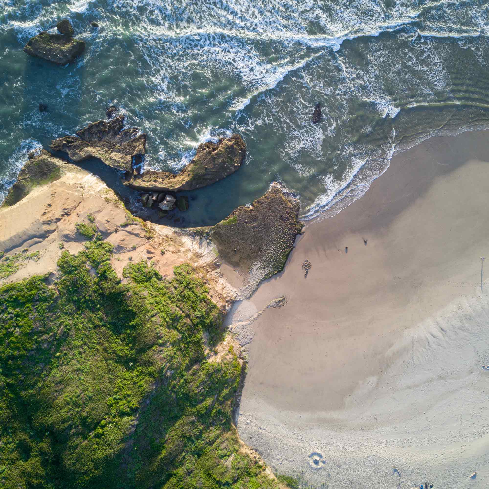 Luftaufnahme von Wellen, die an einem Strand brechen.